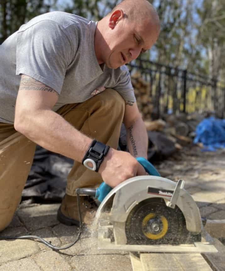 carpenter concentrating on cutting board with circular saw wearing bullseye brace wrist band
