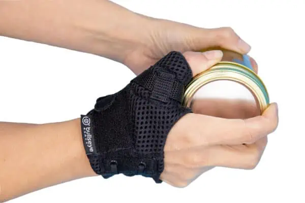Bullseye Brace Thumb Brace on hand while opening a jar. Wearing the CMC brace helps relieve pain associated with the twisting motion of opening a jar.