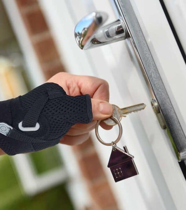 woman's hand holding house key about to unlock door wearing Bullseye Brace thumb brace