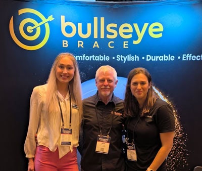 Bullseye founder, Jeff Stearns, with 2 hand therapists in front of Bullseye booth at tradeshow